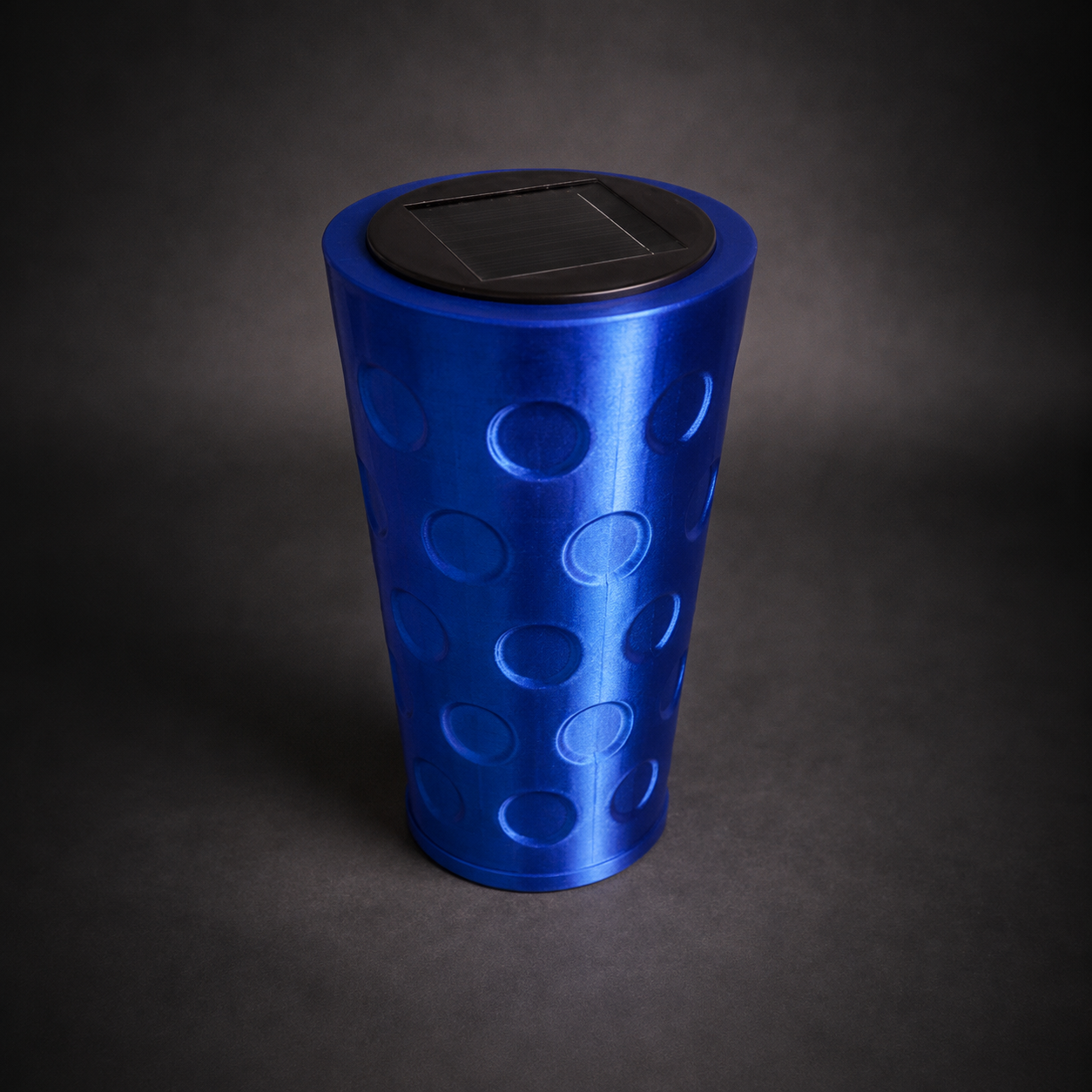 Blaue Dubbeglas Solarlampe mit Solarmodul auf dunklem grauen Studiohintergrund als hochwertiges Produktfoto.